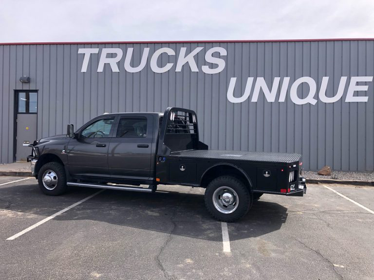 A truck is parked in front of a building that says `` trucks unique ''. | Truck Unique