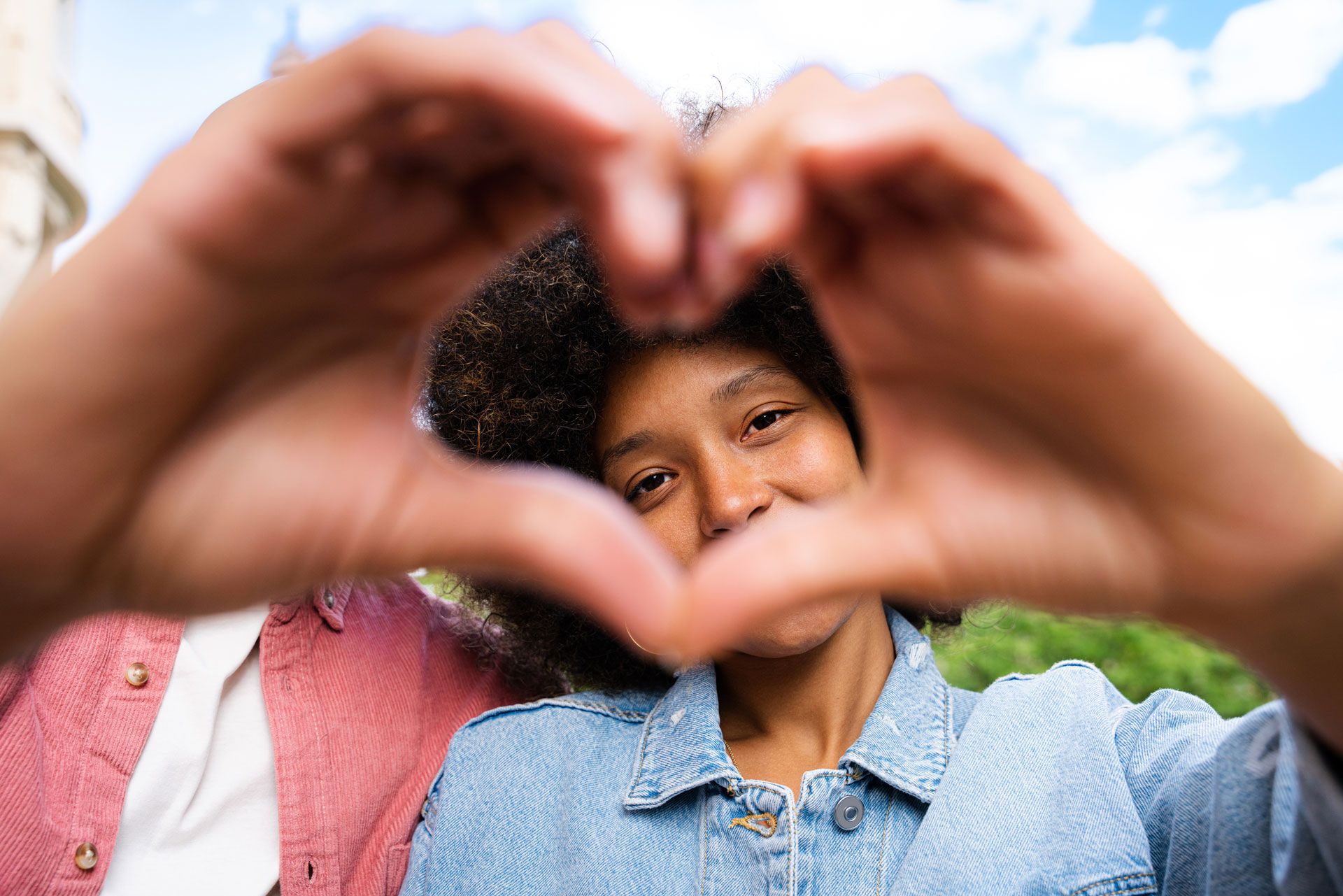 A woman is making a heart shape with her hands.
