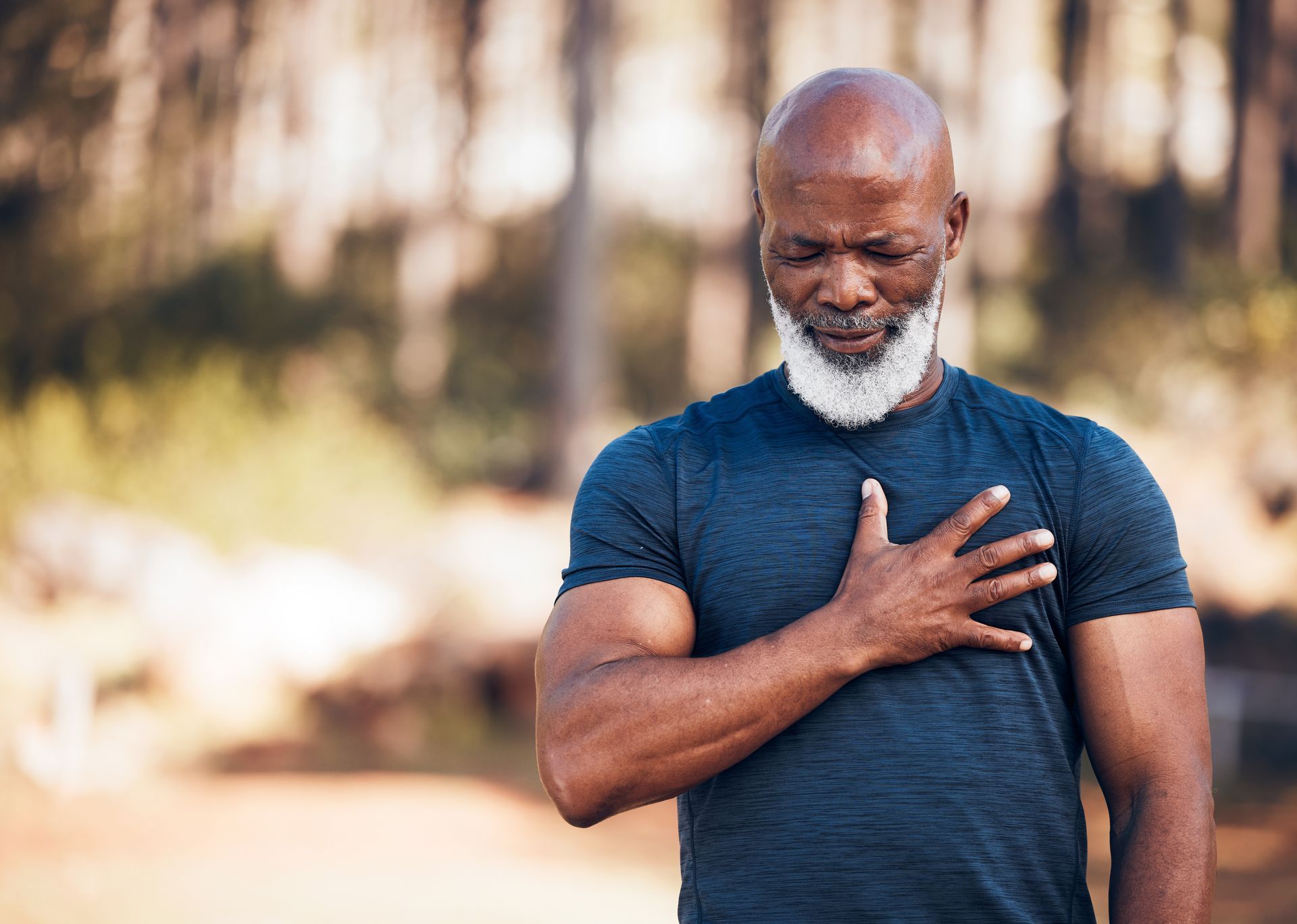 A man with a beard is holding his hand to his chest.
