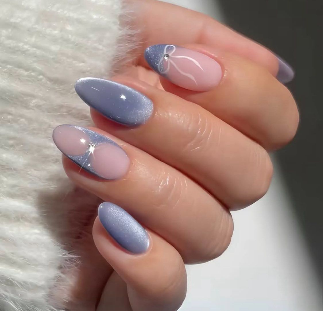 Manicured almond-shaped nails in periwinkle, featuring delicate white ribbon accents and silver glitter details.