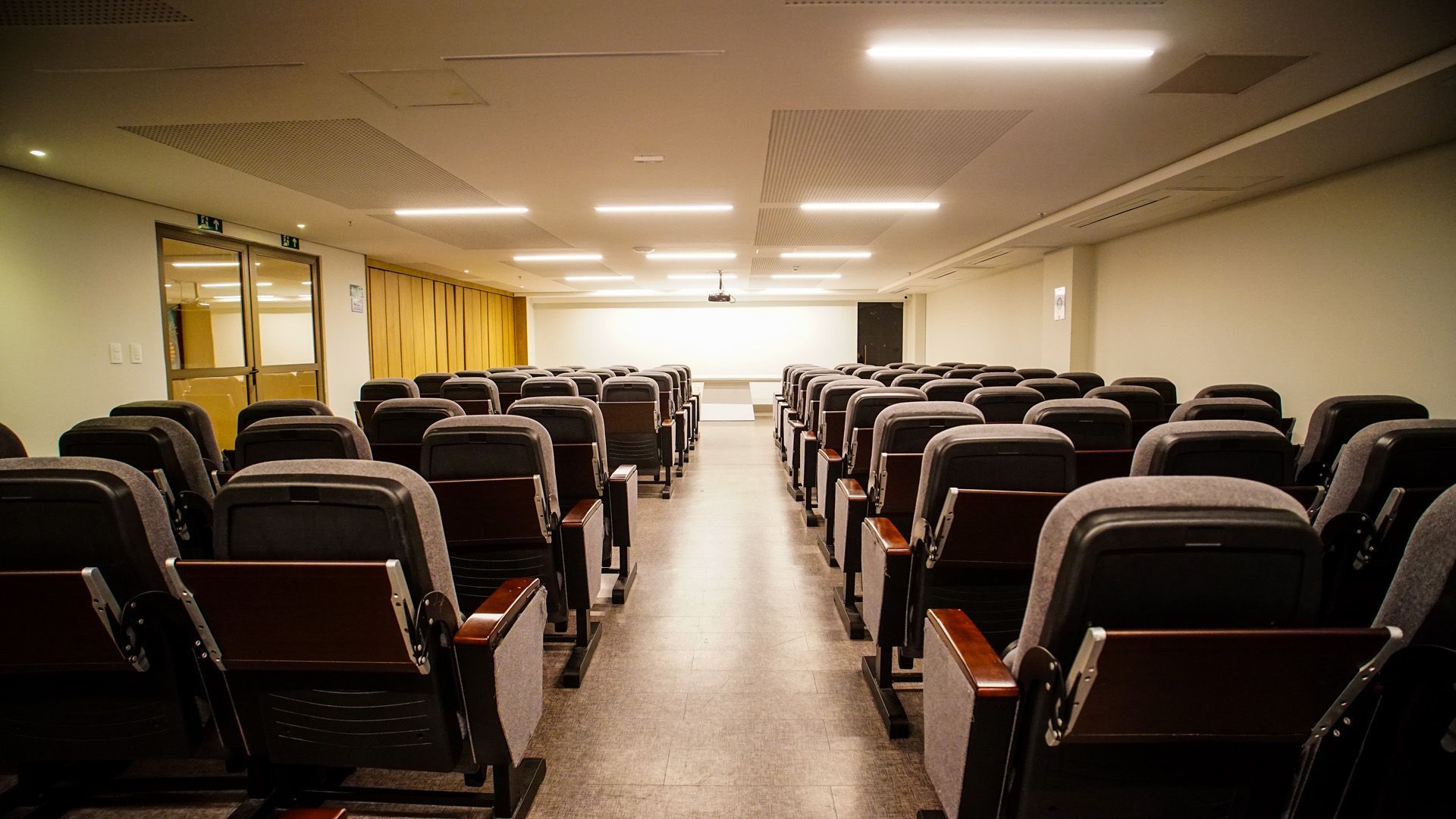 Pátio entre edifícios, com piscina e vista para o mar, sob um céu azul.