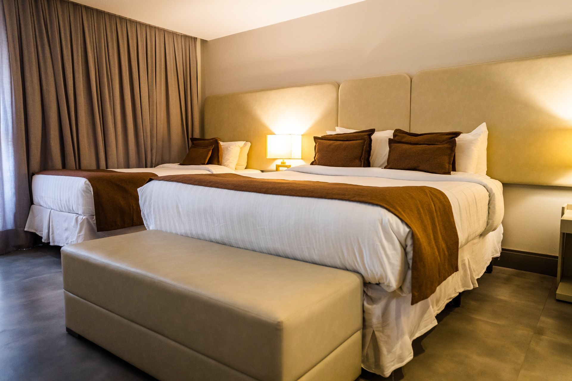 Pátio entre edifícios, com piscina e vista para o mar, sob um céu azul.