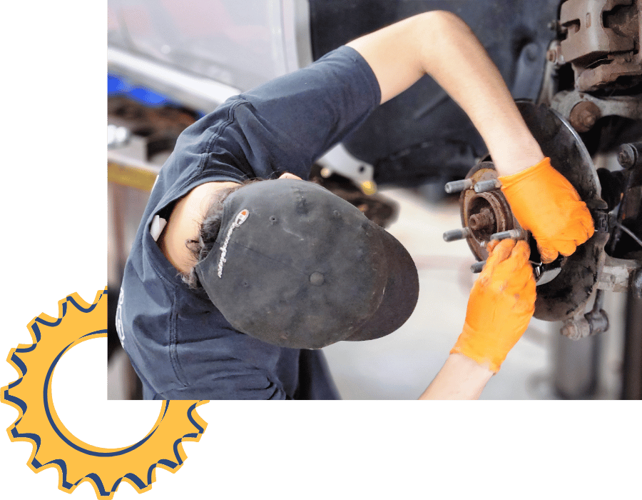 Technician wearing gloves replacing brake pads and servicing the brake assembly.