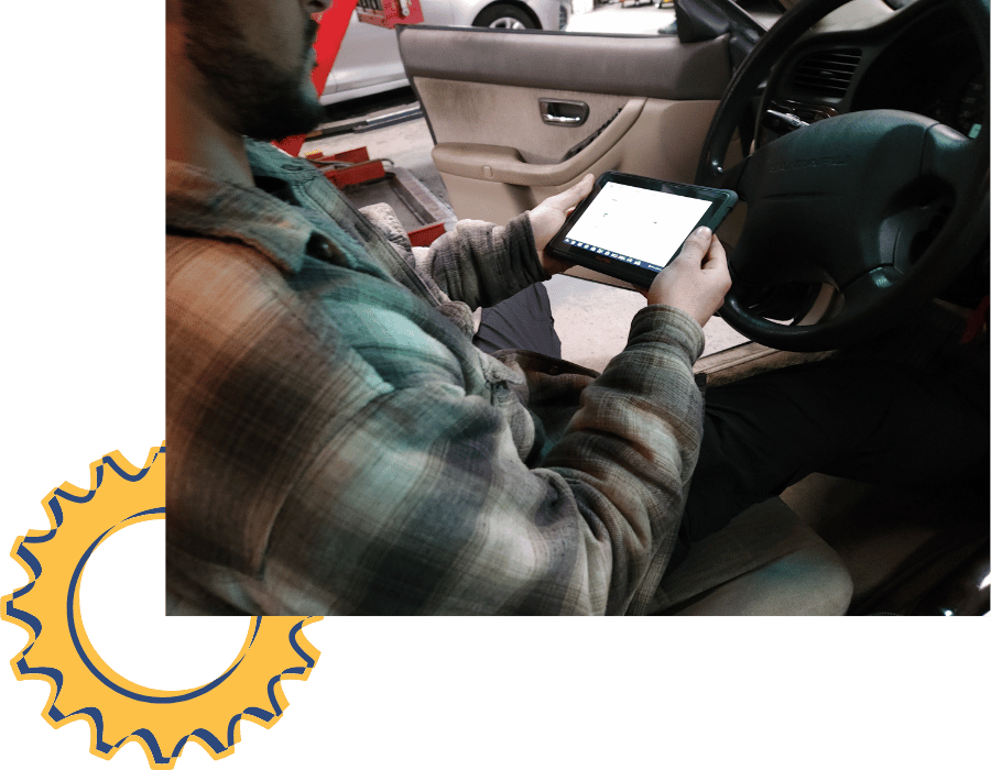 Mechanic using a tablet inside a vehicle to perform air conditioning system diagnostics.