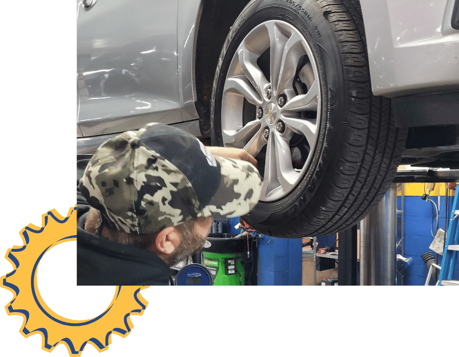 Technician inspecting Chevrolet vehicle wheel and tire on lift during service.