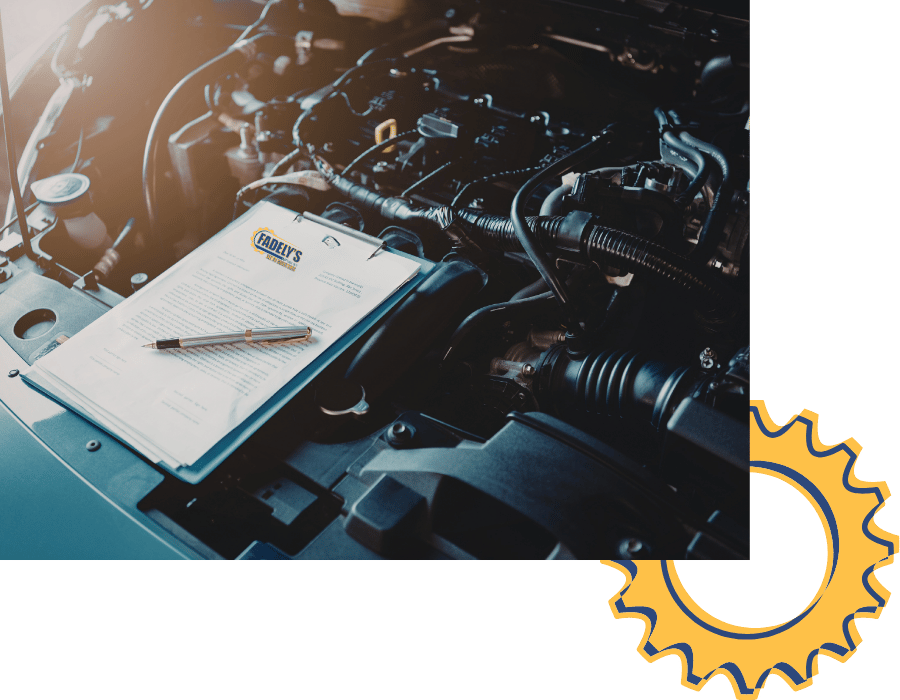 Technician reviewing vehicle inspection checklist on engine during state inspection.