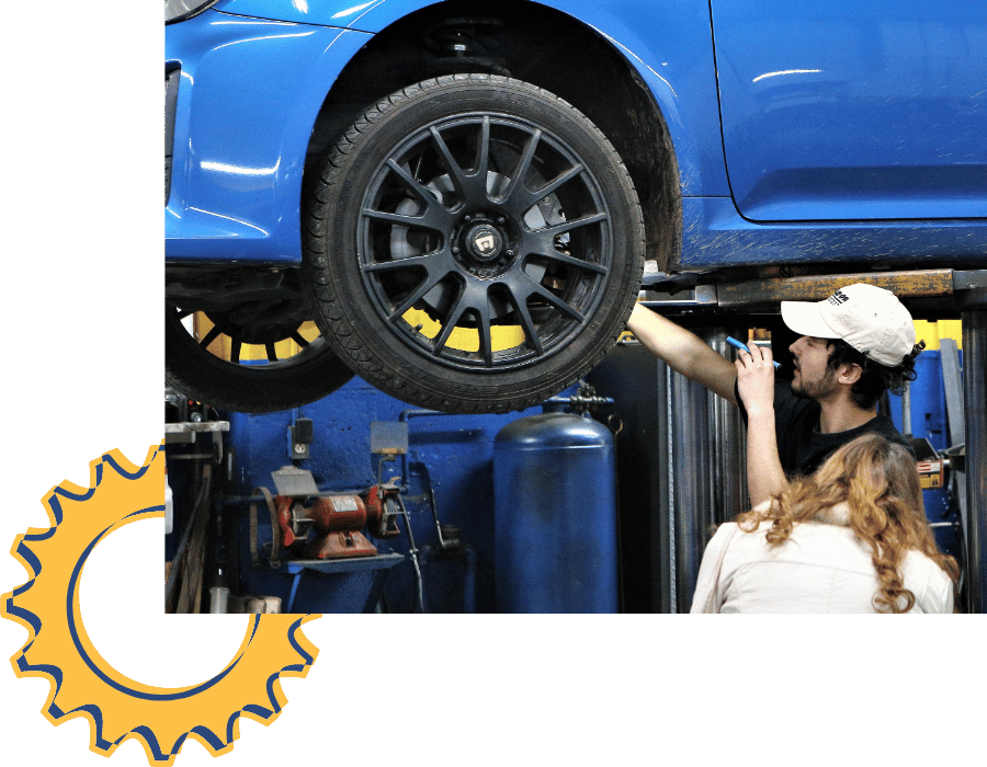 Black SUV elevated on a hydraulic lift for state inspection and maintenance check.