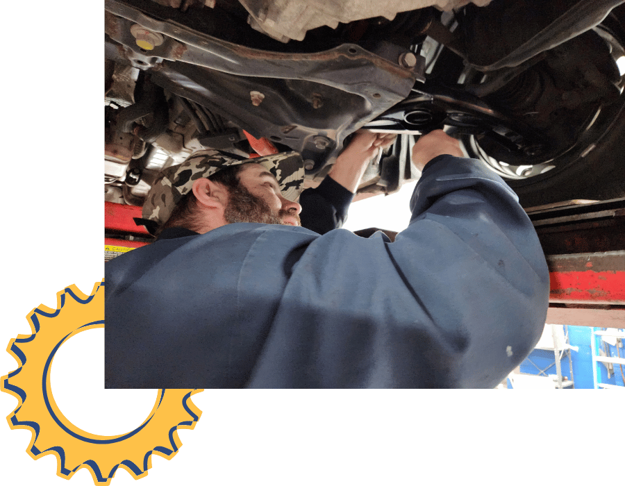 Technician inspecting suspension components under a raised vehicle.