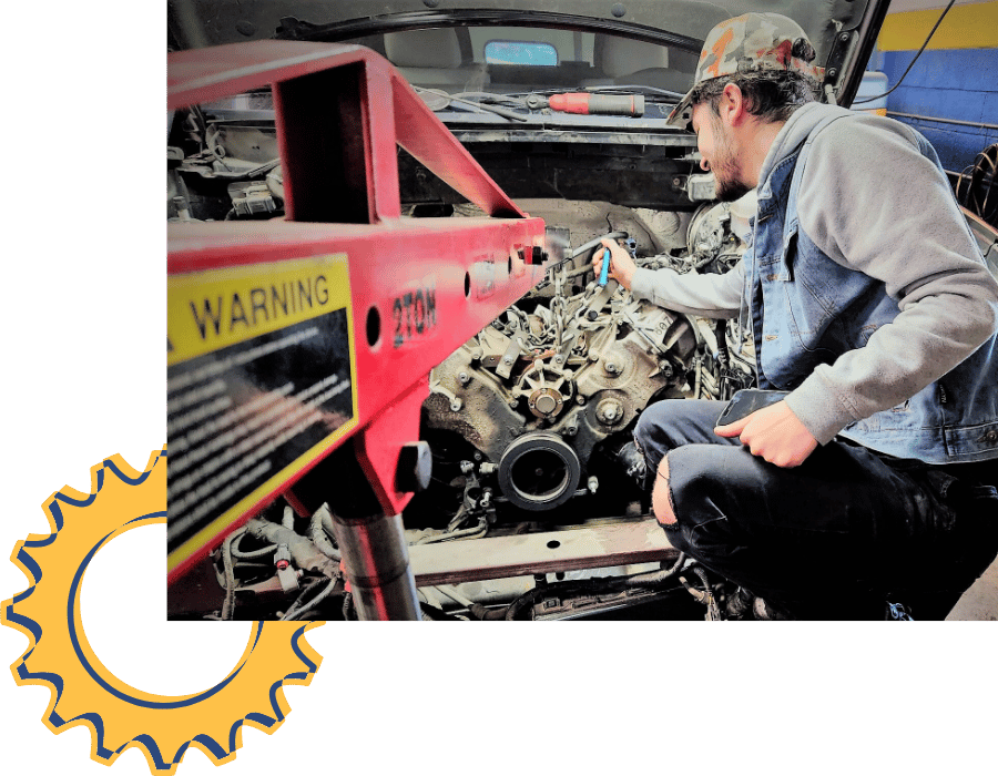 Technician performing transmission replacement on a vehicle in the shop.