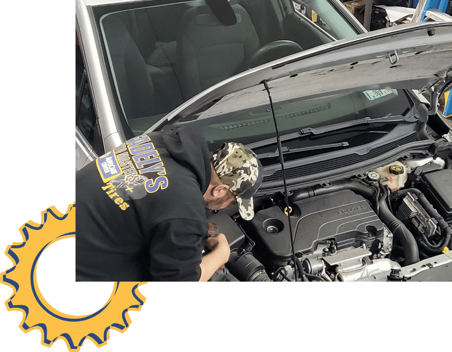 Auto technician performing engine diagnostics on vehicle in service bay.