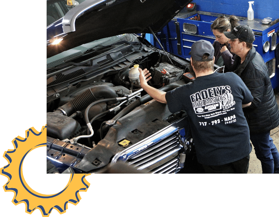 Technician reviewing engine components with customers during vehicle inspection.