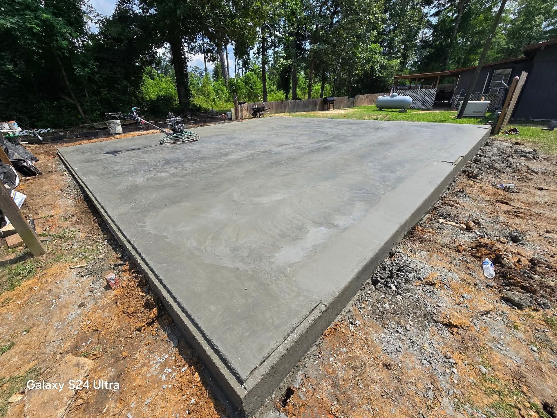 Freshly poured concrete foundation on dirt, awaiting a building. Outdoors, sunny.