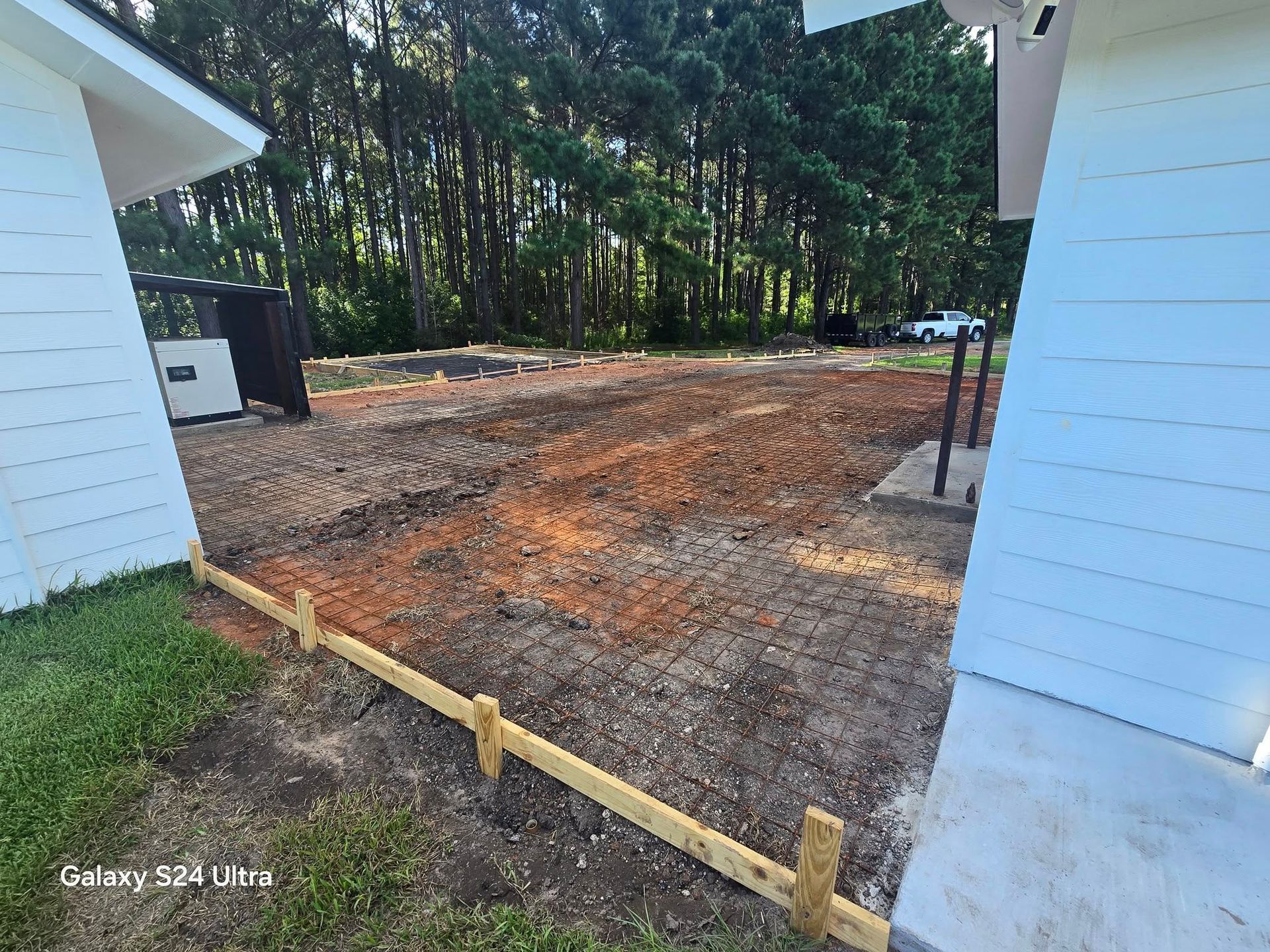 A dirt area framed by wooden posts, with buildings on either side and trees in the background.