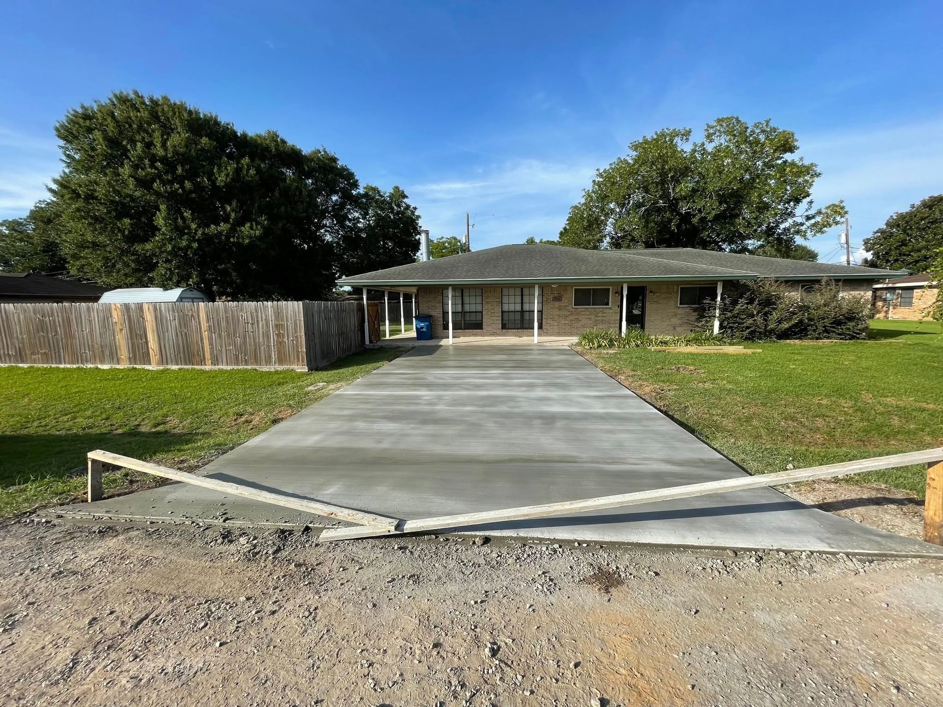 Newly poured concrete driveway leading to a one-story house.