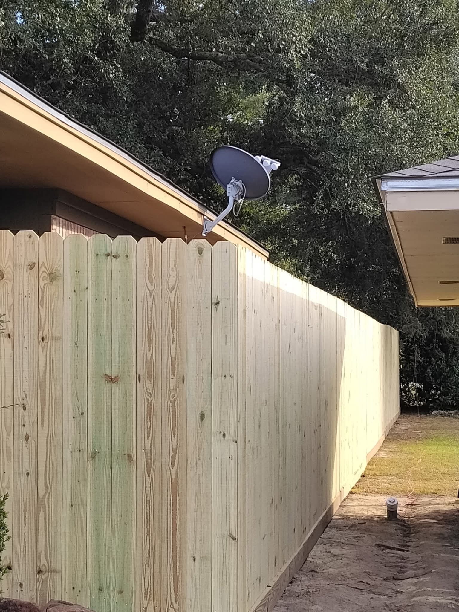 Wooden fence with a satellite dish mounted on it.