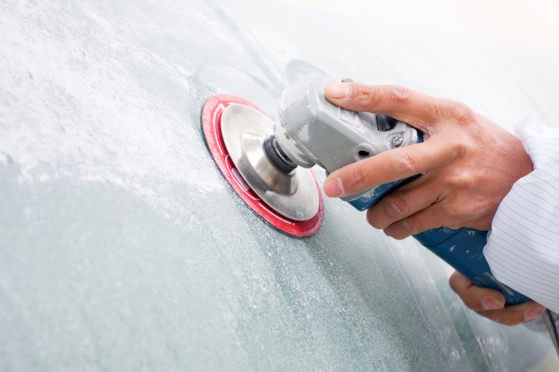 Una persona sta lucidando un'auto con una smerigliatrice.