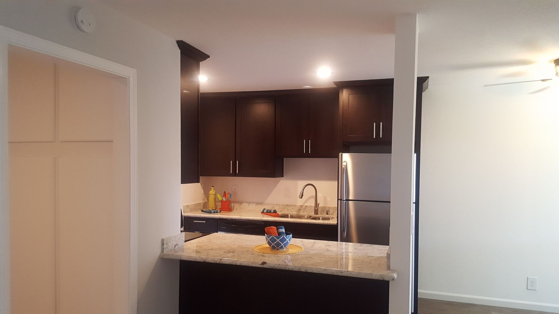 A kitchen with brown cabinets and a stainless steel refrigerator