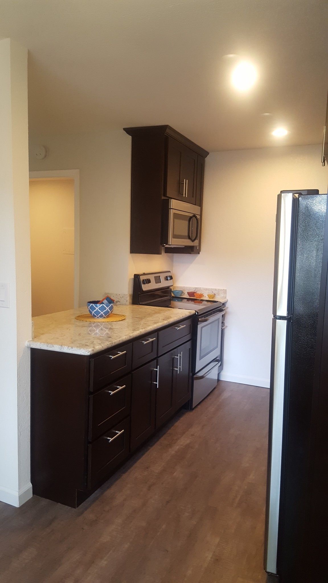 A kitchen with a refrigerator , stove , microwave and sink.