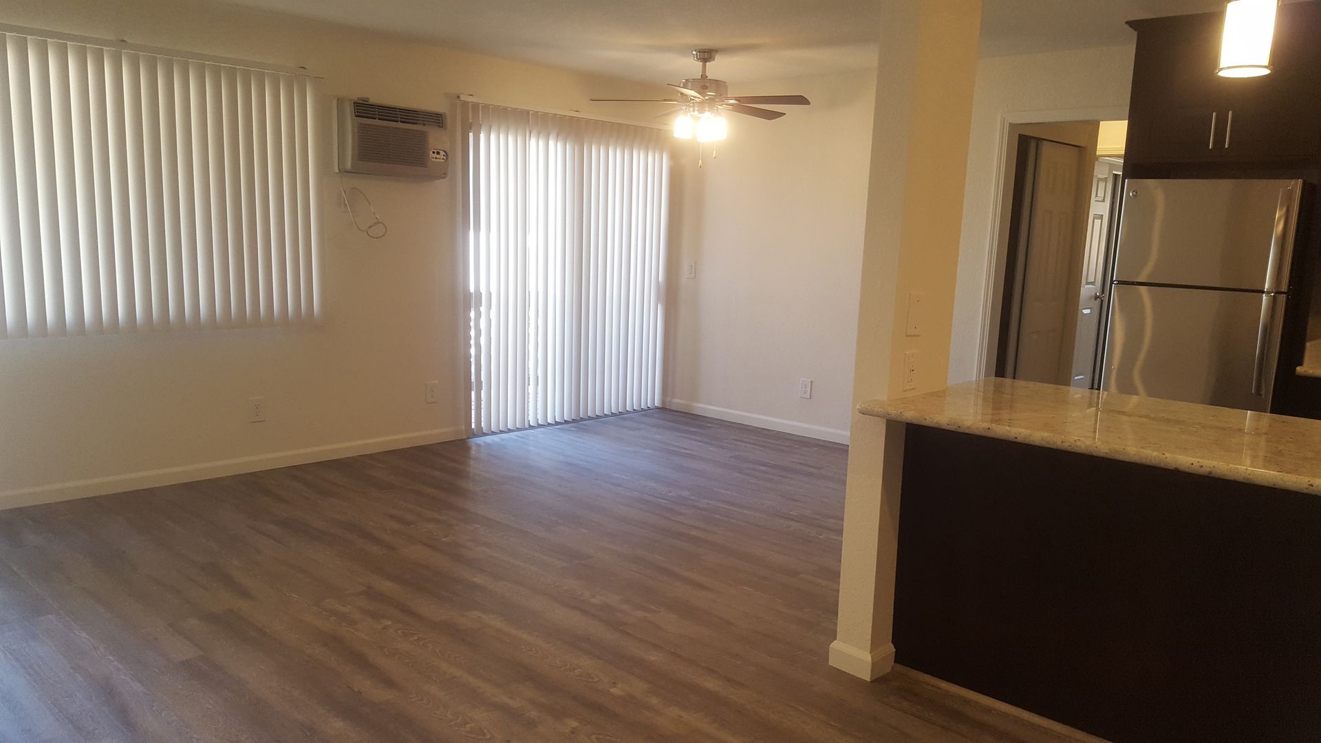 An empty living room with sliding glass doors and a ceiling fan.