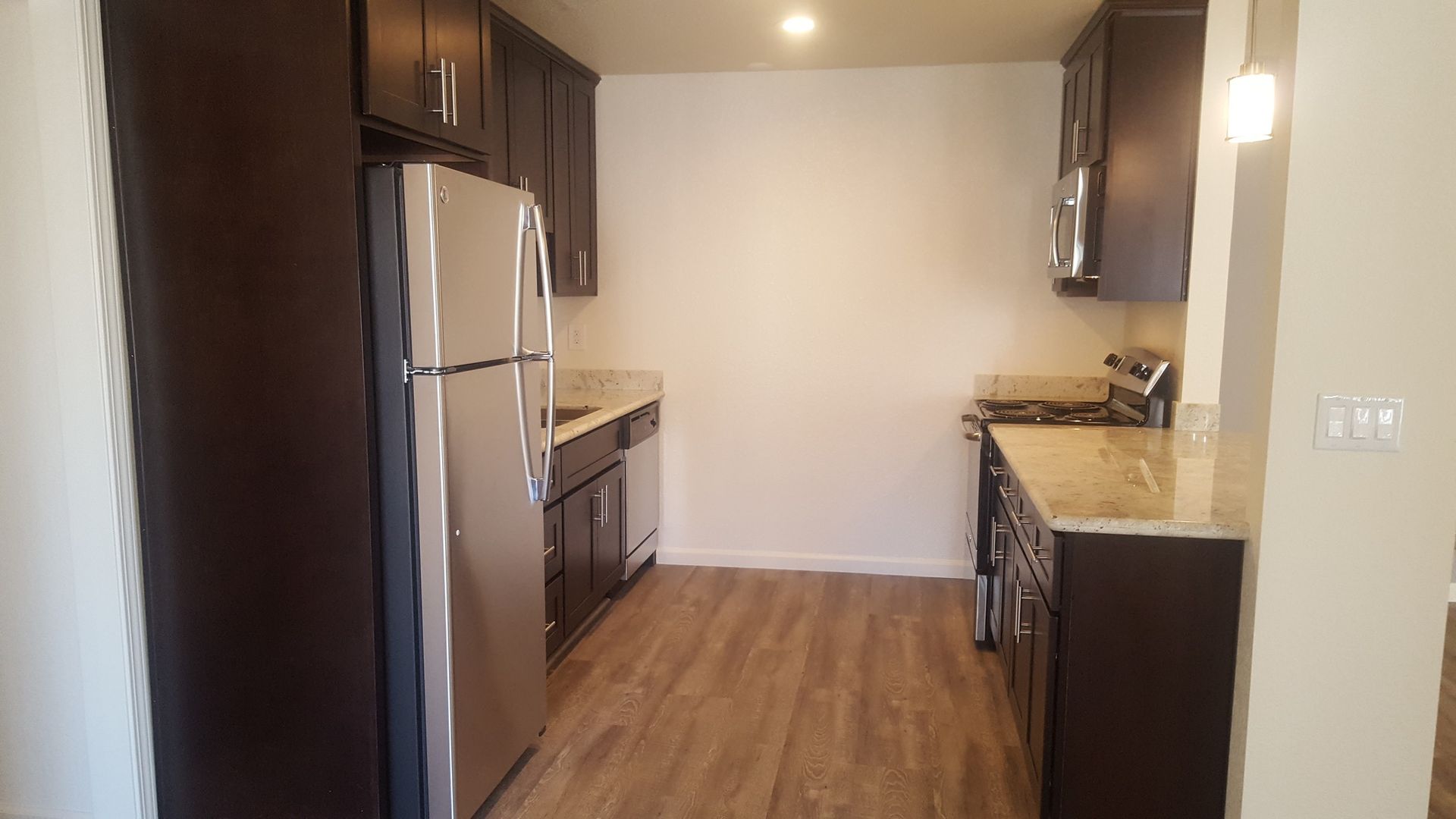 A kitchen with stainless steel appliances and wooden floors.
