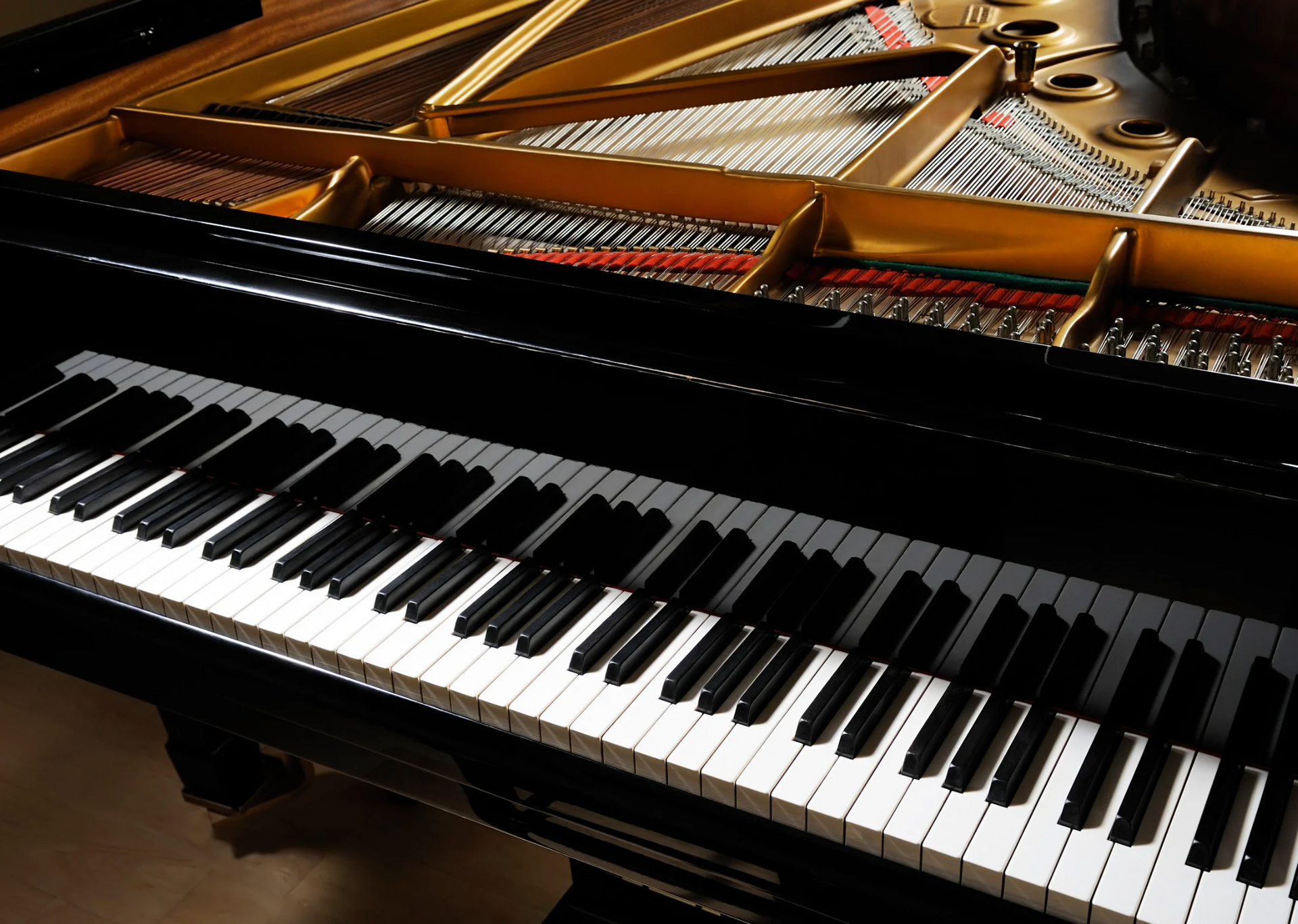 Grand piano with open lid, showing keys, strings, and soundboard in a well-lit room.