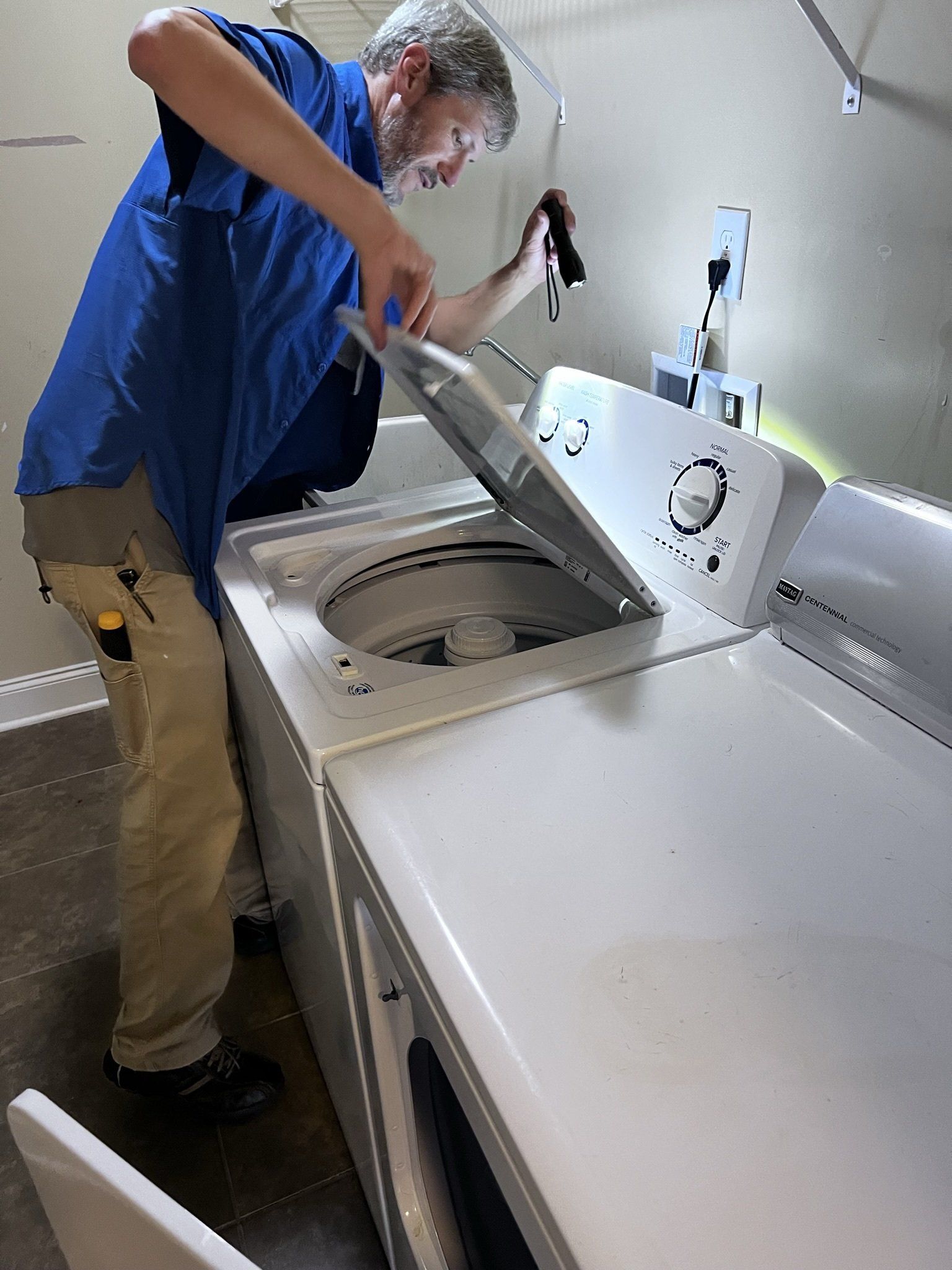 A man is working on a washing machine in a laundry room.