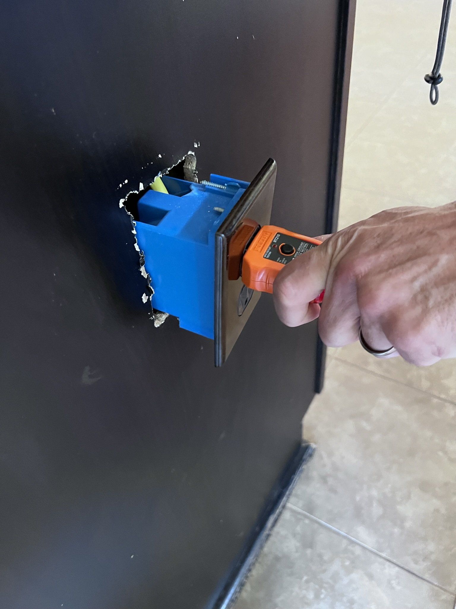 A person is installing a light switch in a wall.