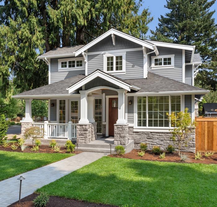 A large gray and white house with a large lawn in front of it