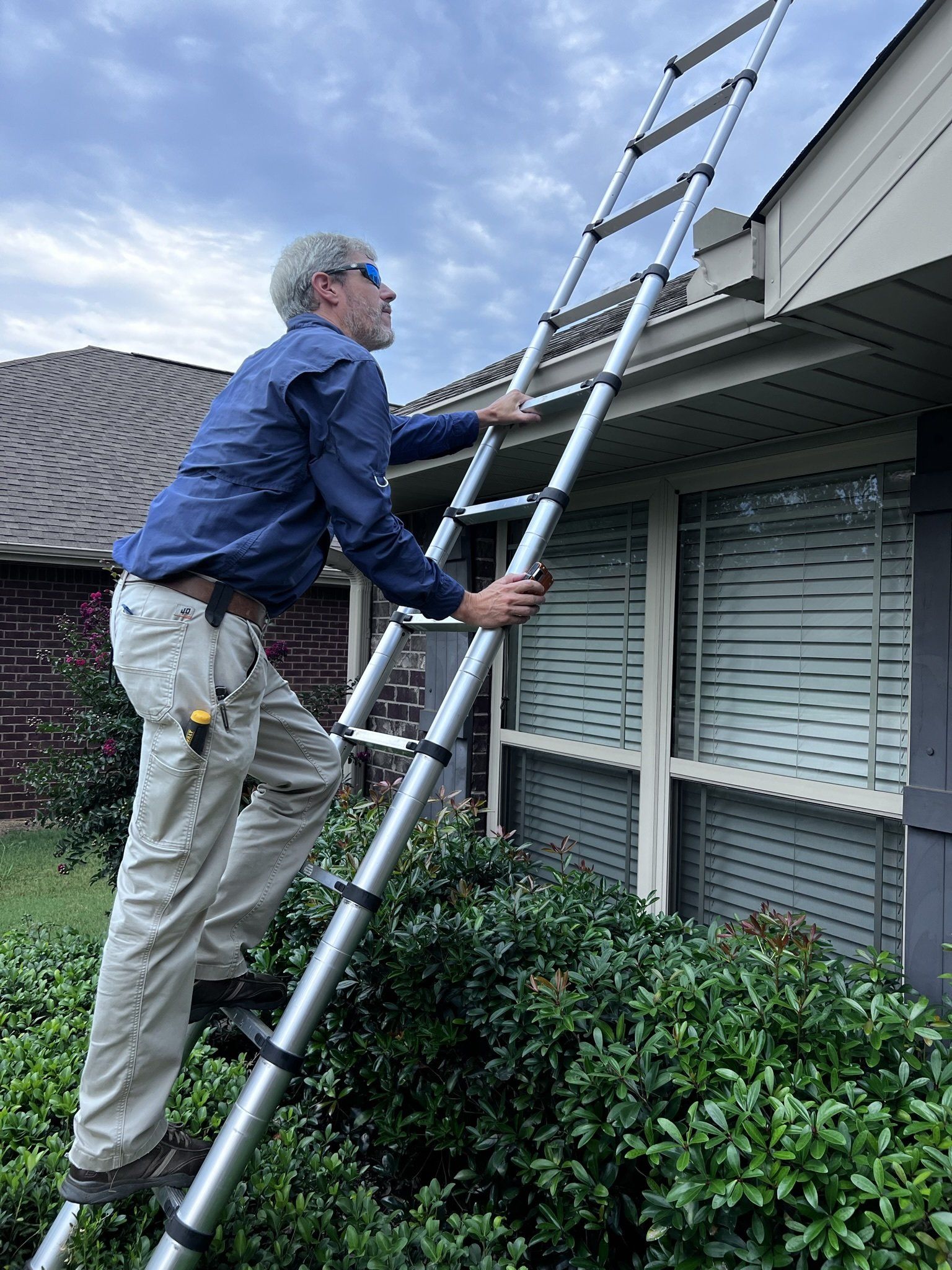 A man is climbing a ladder to reach the roof of a house.