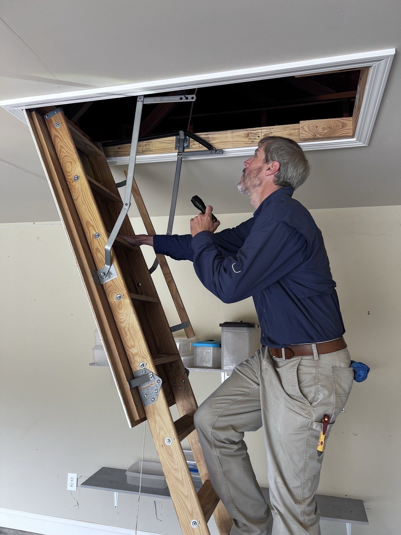 A man is climbing up a wooden ladder in a garage.