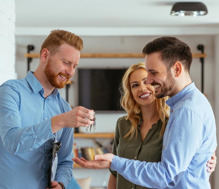 A man is giving a couple of keys to their new home.