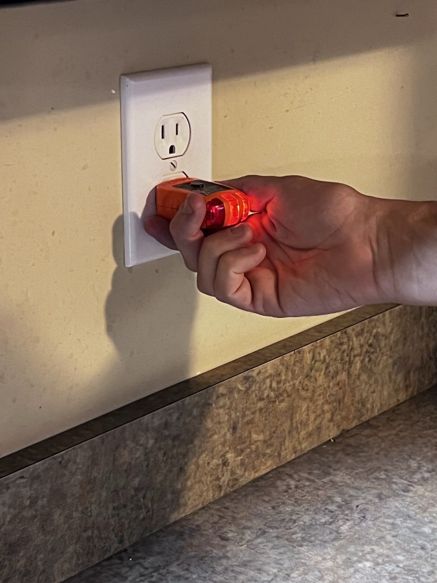 A person is plugging a screwdriver into an electrical outlet.
