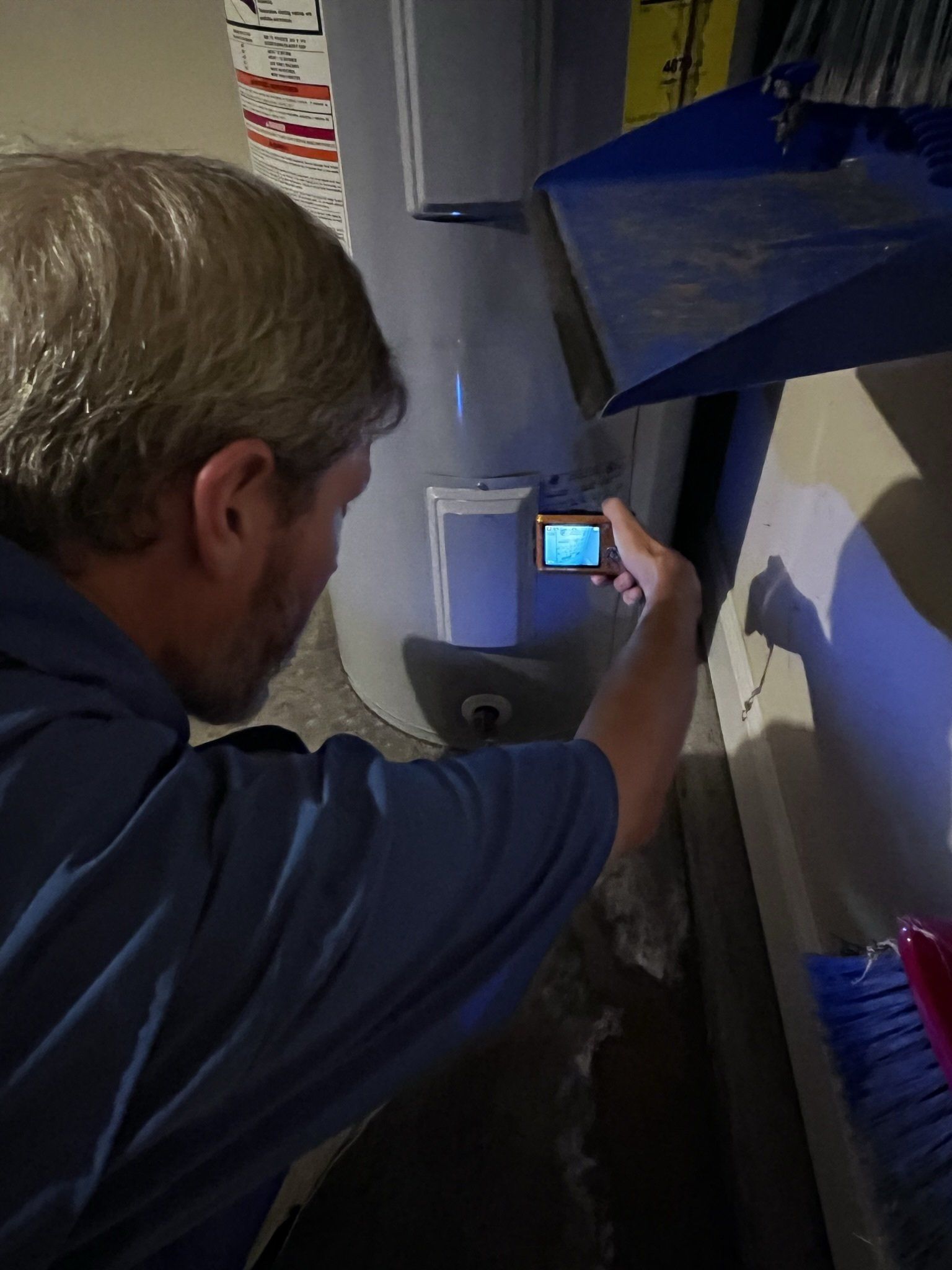 A man is taking a picture of a water heater with a camera.