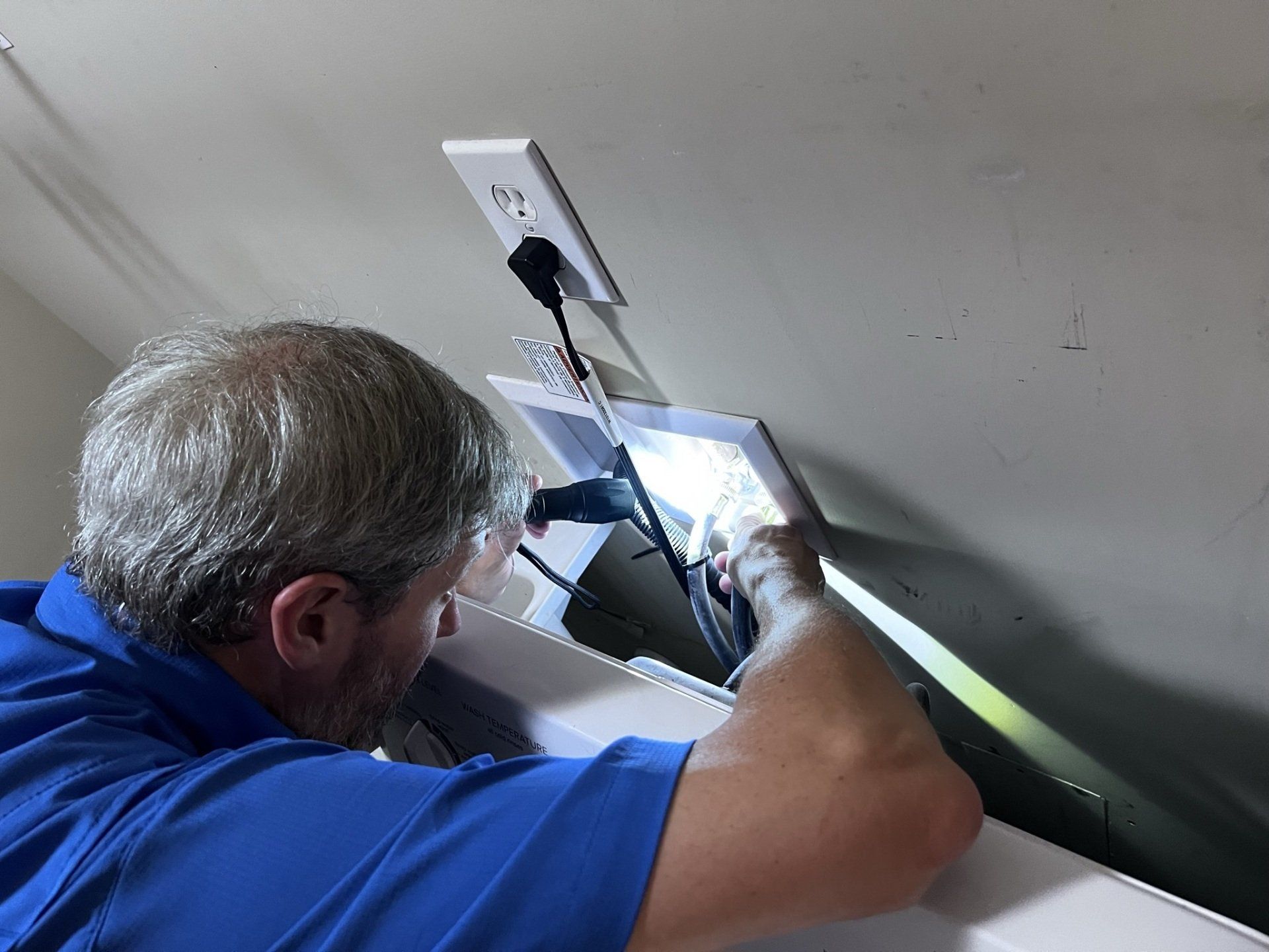 A man in a blue shirt is working on a light fixture