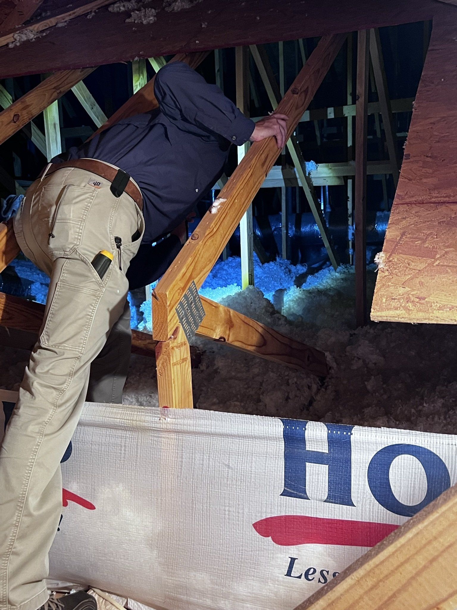 A man is standing in an attic next to a sign that says ho