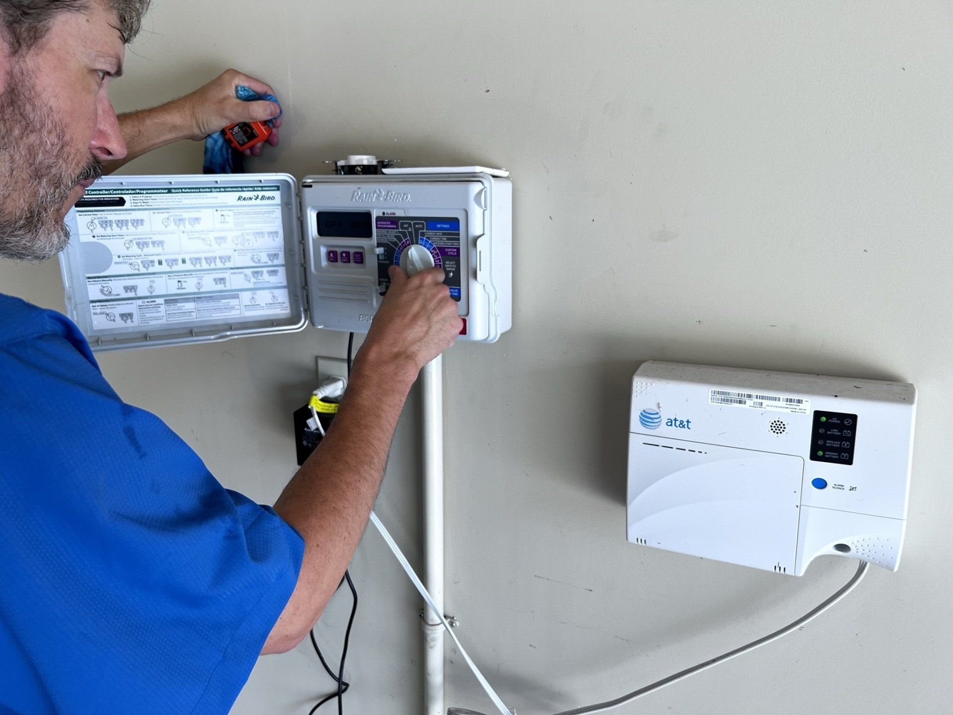 A man in a blue shirt is working on a sprinkler system.