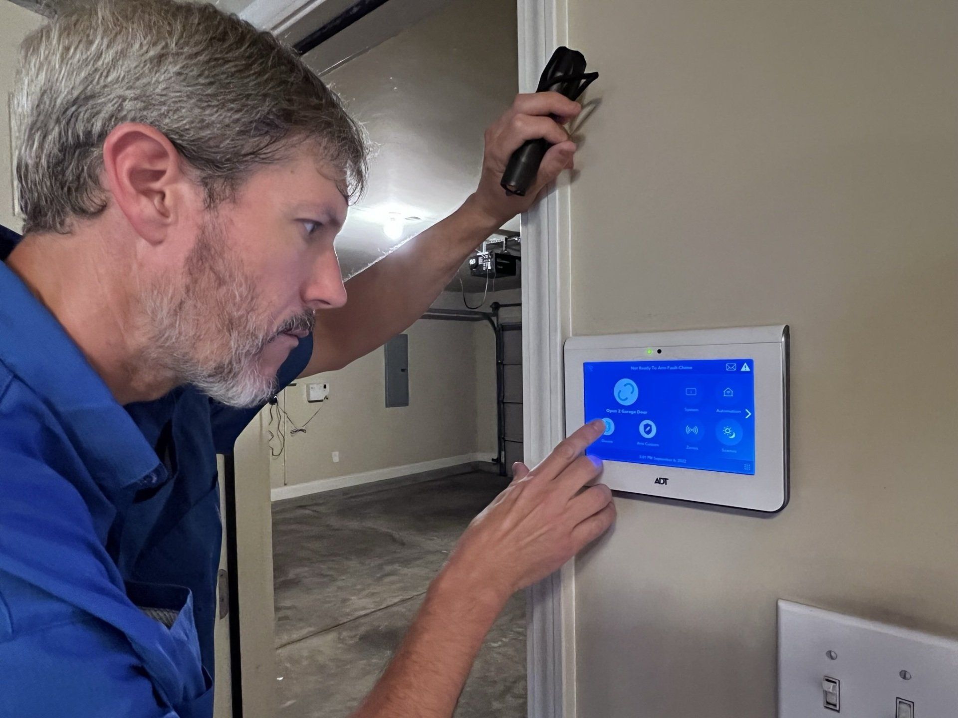 A man is installing a thermostat on a wall.