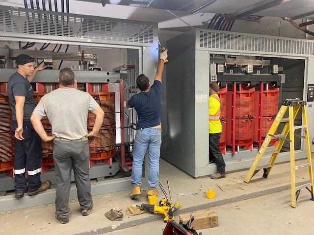 A group of men are working on a transformer in a room.