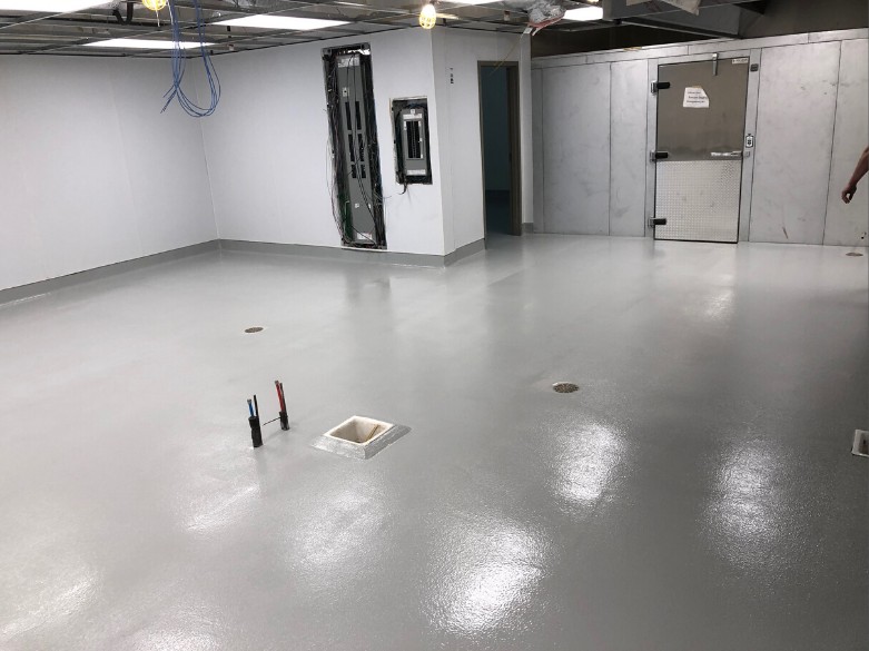 Covered outdoor patio with black ceiling and gray speckled flooring.