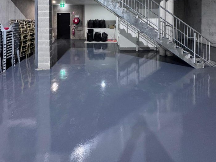 Epoxy floor of a modern industrial space with a staircase leading to a small upper level. 