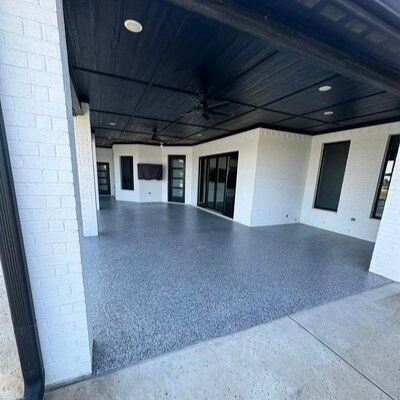 Covered outdoor patio with black ceiling and gray speckled flooring.