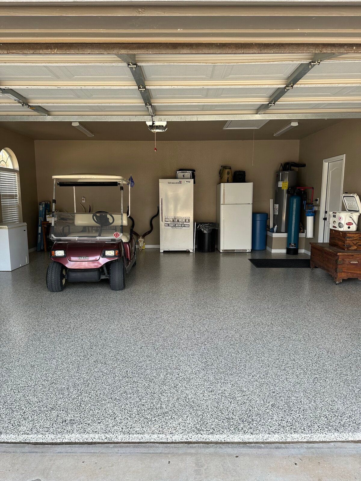 Garage interior with epoxy floor, a golf cart, and various appliances and storage.