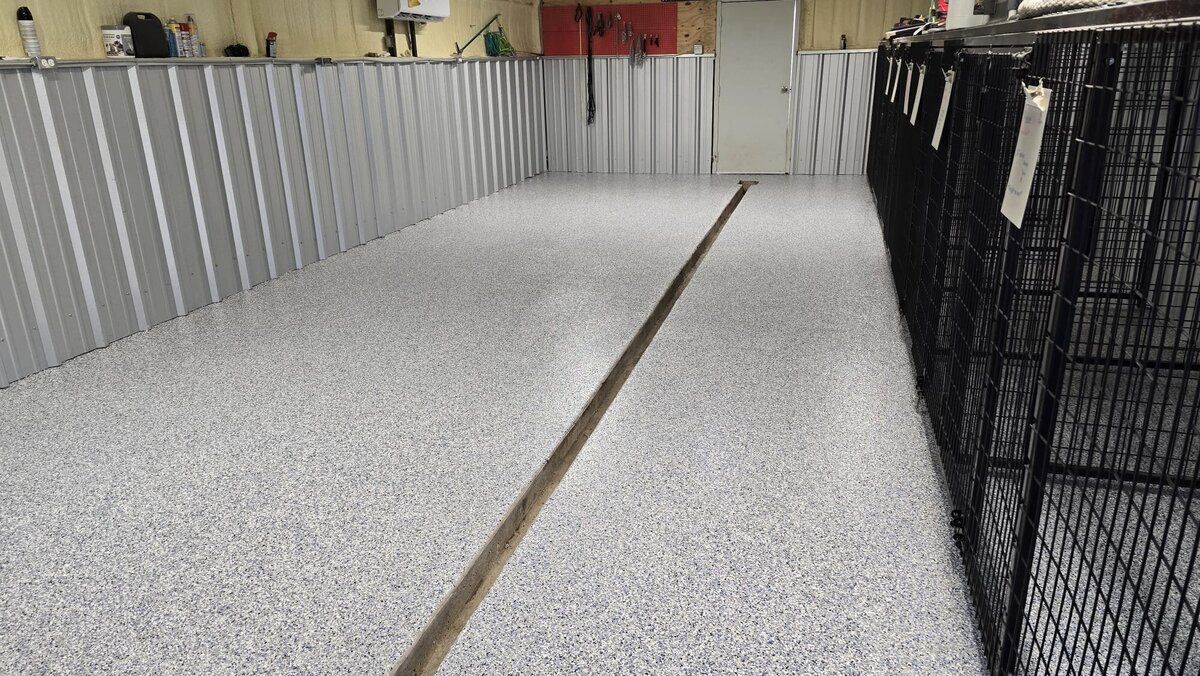 Dog kennel hallway with metal walls, epoxy floor, and cages.