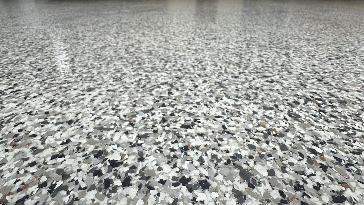 Epoxy flooring with speckled gray, white, and black chips, creating a textured surface.
