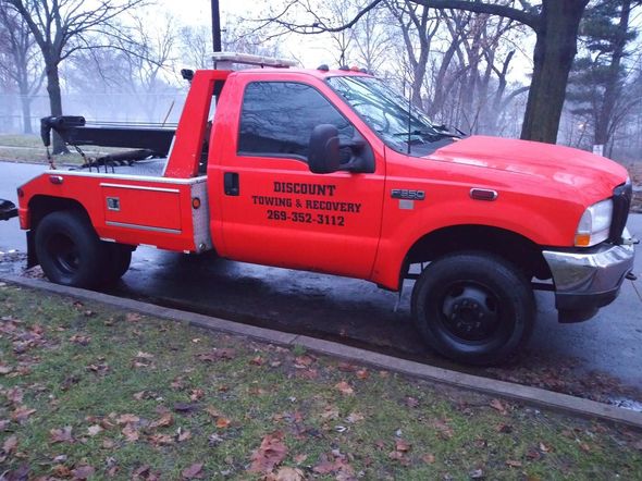 A red tow truck is parked on the side of the road