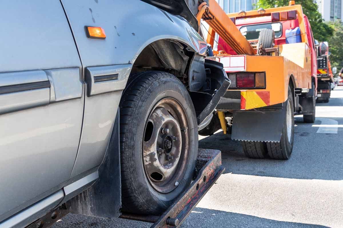 A car is being towed by a tow truck on a city street.