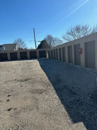 Storage units in a gravel lot under a bright blue sky.