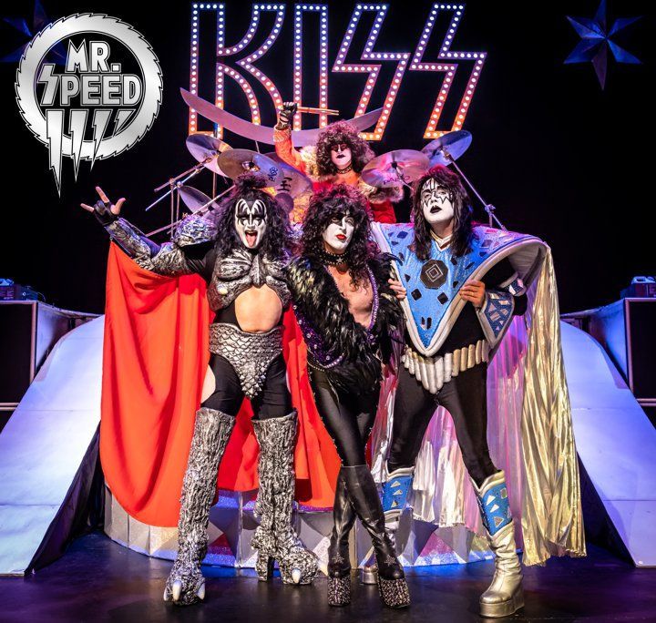 a group of people standing on a stage in front of a sign that says kiss