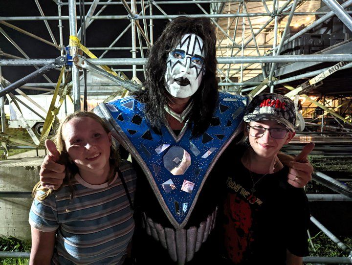 a man in a kiss costume is posing for a picture with two children .