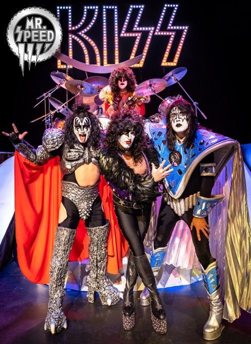 a group of people standing on a stage in front of a sign that says kiss